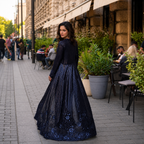 Woman in a dark blue lace dress walking on a city street.